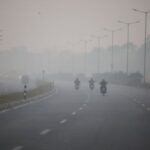 Vehicles move on a road on a smoggy morning amid
