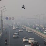 Vehicles ply on a highway, on a smoggy morning amid