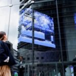 A woman walks past a stock quotation board at a