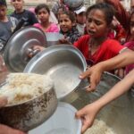 Palestinians wait to receive food cooked by a charity kitchen,