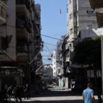 Palestinians react as a missile falls towards a house during