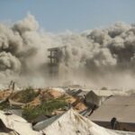 Smoke and flames rise as a residential building collapses after
