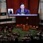 A screen displays Hong Kong Chief Executive John Lee as