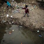 FILE PHOTO: Boys play near an open sewer at a