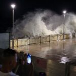 A resident takes photos of rough waves from the shore