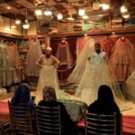 Shopkeepers display bridal dresses to customers at a shop in