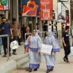 People walk outside shopping mall in Karachi