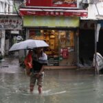 A man holds an umbrella as he wades through a