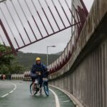 A cyclist looks at a broken fence on a cycle