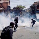 Protests throw back teargas canisters lobed by riot police officers