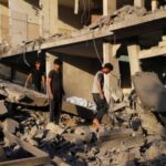 Palestinians inspect the site of Israeli strikes on houses at