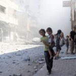 Palestinians inspect the site of Israeli strikes on a house,
