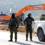 Israeli soldiers stand guard during the construction of Israeli bypass