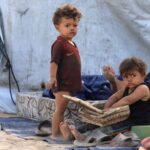 Displaced Palestinian children shelter on the side of a raod,