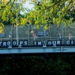 Activists wave to vehicles from an overpass on the Henry