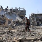 Palestinian walks amids rubble as he inspects the damage in