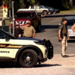 Law enforcement officers guard a gate outside the Accurate Energetic