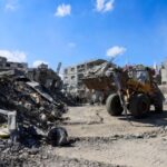 Heavy machinery removes debris from a street, amid a ceasefire