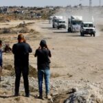 Red Cross vehicles escort trucks transporting the bodies of Palestinians