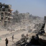 Palestinians walk past the rubble of destroyed buildings, in Gaza