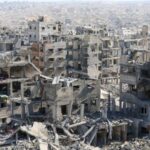 Palestinians walk past the rubble of destroyed buildings, in Gaza