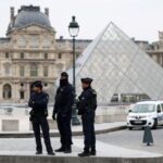 Police stand near the pyramid of the Louvre museum after