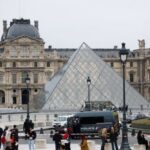 Police stand near the pyramid of the Louvre museum after