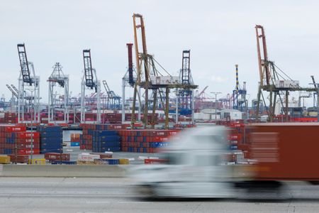 Semi-truck drives past Chinese shipping containers at the Port of
