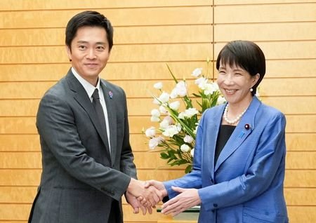 Japan's new Prime Minister Sanae Takaichi shakes hands with Hirofumi