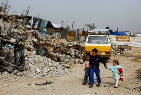 Palestinians walk past the rubble of residential buildings destroyed during