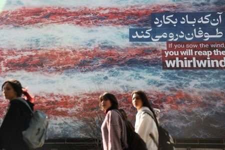 Iranian women walk past an anti-U.S. billboard in Tehran