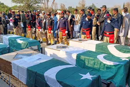 Police officers and residents gather beside Pakistani flag-draped coffins of