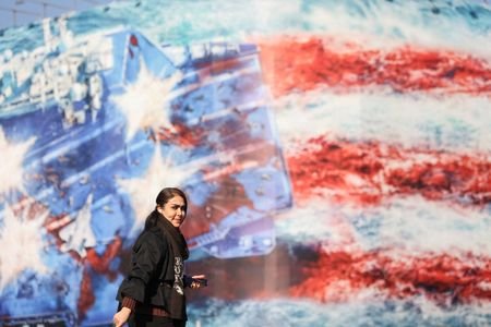 A woman walks past an anti-U.S. billboard on a street