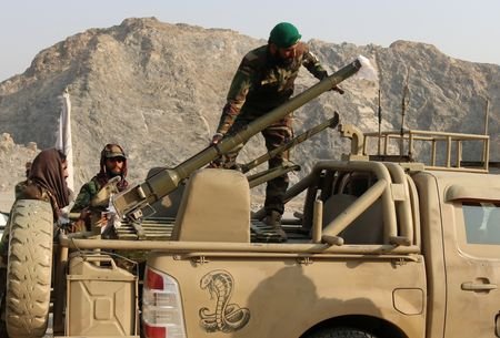 Taliban soldiers load a rocket launcher in a vehicle near