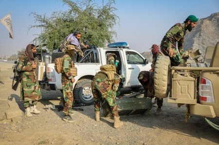 Taliban soldiers load a rocket launcher in a vehicle near