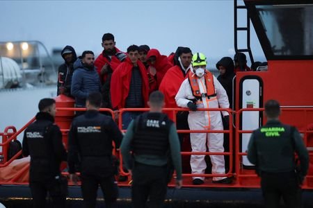 Migrants disembark from a Spanish Coast Guard vessel at the