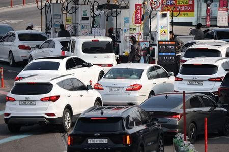 People fill up their car at a gas station in
