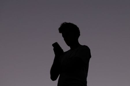 A man uses a mobile phone at dusk in Brisbane