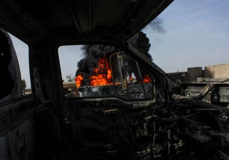 Thick black smoke is seen through a destroyed truck at