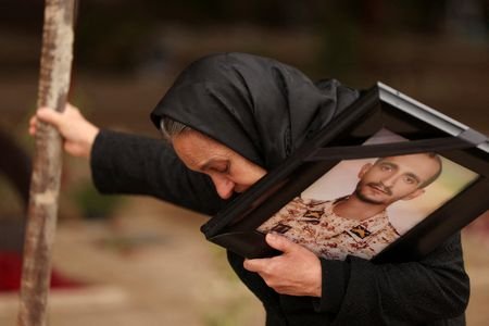 Marzia Rezaei reacts while standing near the grave of her
