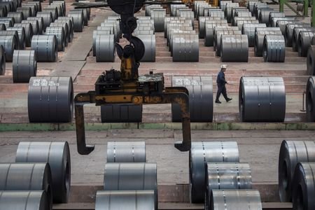Worker walks past steel rolls at the Chongqing Iron and