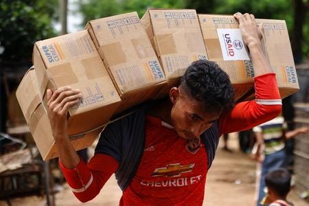 A Rohingya man carries USAID packages as he transports them
