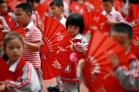 Children perform a Kung Fu Fan dance while carrying plastic