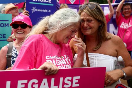 People react after Britain's parliament voted in favour of a