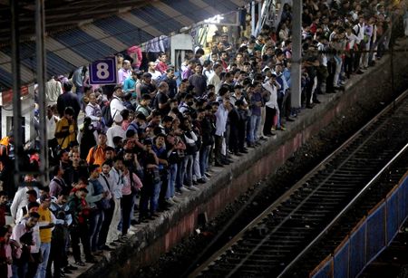 Commuters crowd on a platform as they wait to board