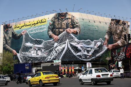 Cars drive near an anti-U.S. billboard in Tehran