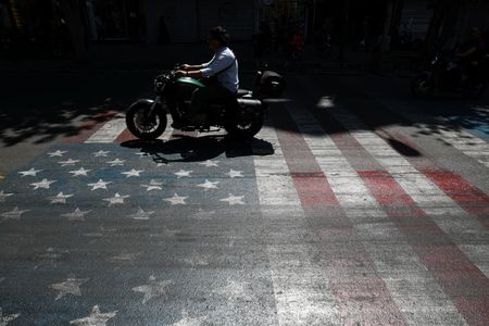 Person rides a motorcycle over a U.S. flag painted on