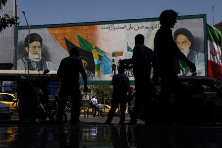 People walk past a mural depicting late Iranian leaders in