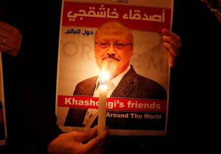 A demonstrator holds a poster with a picture of Saudi