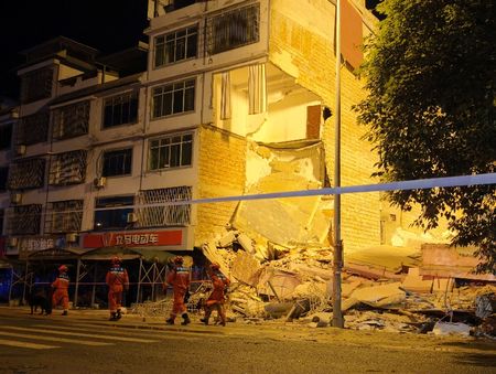 Rescue workers walk past a damaged building following an earthquake